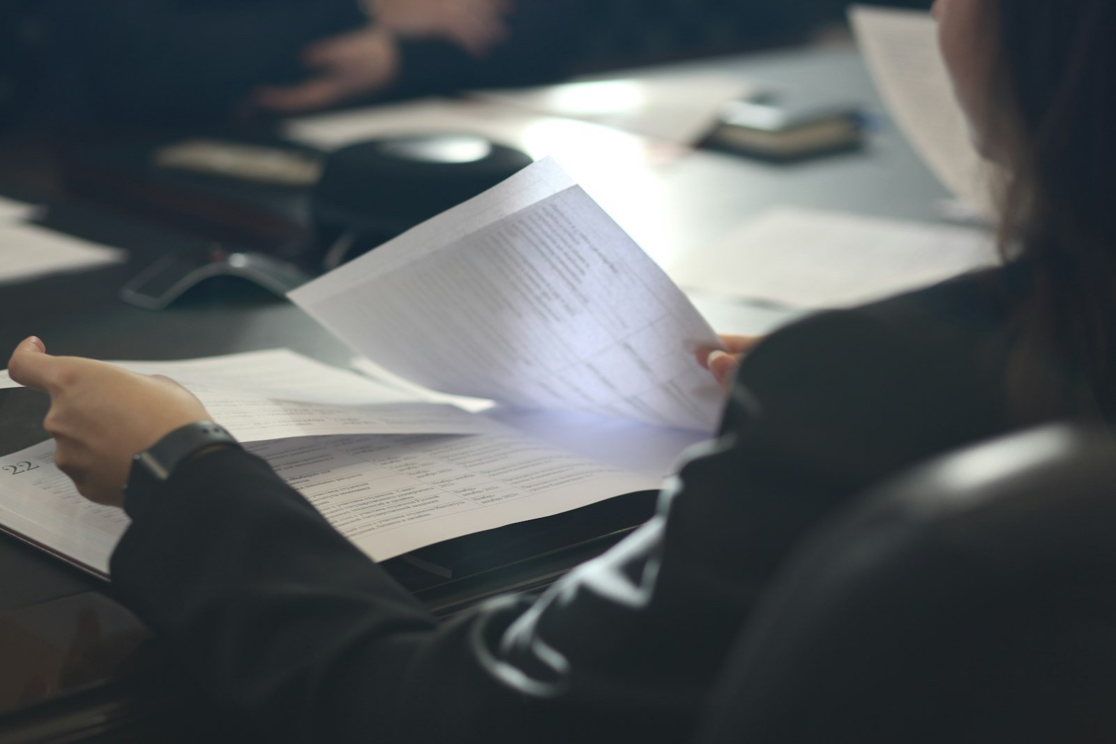 A professional reviewing a printed assessment document at a meeting table