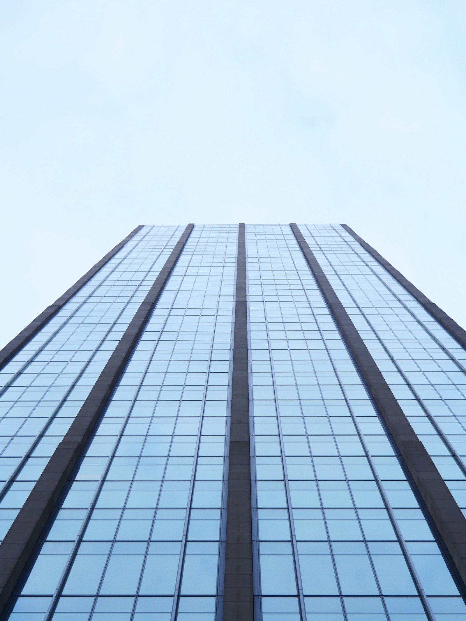 A modern glass office tower seen from below
